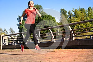 Photo of modern young woman in sports clothing jumping while exercising outdoors