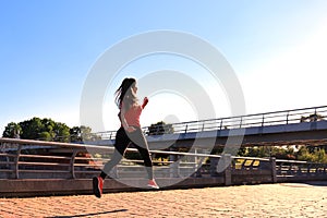 Photo of modern young woman in sports clothing jumping while exercising outdoors