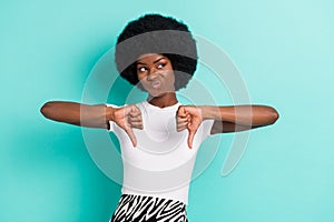 Photo of moody upset dark skin woman looking empty space showing dislikes isolated turquoise color background