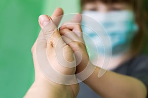 Photo of a mother and child`s hand. A mother holds the hand of a small child. A blurry little girl in a medical mask holds her mot