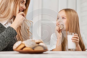 Photo of mother and daughter eating cookies and smile.