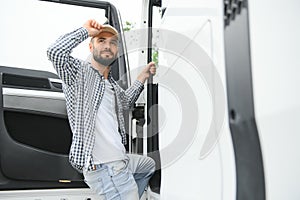 Photo of motivated truck driver entering his semi truck long vehicle. Happy trucker. Transportation service