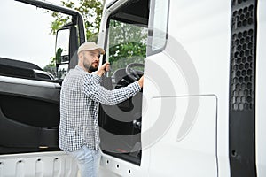 Photo of motivated truck driver entering his semi truck long vehicle. Happy trucker. Transportation service