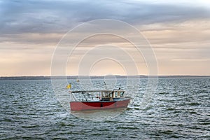 Photo of motor fishing boat under dark clouds with yellow flag photo