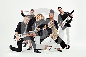 Photo of multi ethnic music band in studio.Musicians and woman soloist posing over white background