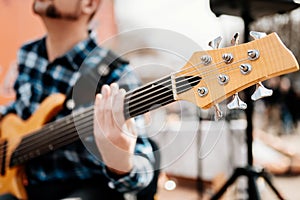 Photo of musician playng on six string fretless bass guitar on the street in front of people.