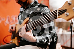 Photo of musician playng on six string fretless bass guitar on the street in front of people.