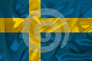 Photo of the national flag of the state of Sweden on a luxurious texture of satin, silk with waves, folds and highlights, close-up
