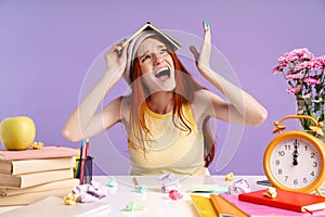 Photo of nervous student girl holding exercise book on her head