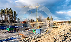 Photo of new bridge building site with timbering construction for further filling it with concrete. Yellow crane tower, blue