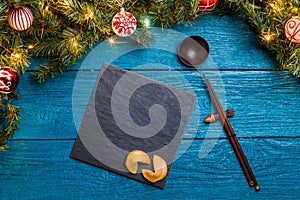 Photo of New Year branches of fir, black board, sticks for sushi, cookies with prediction