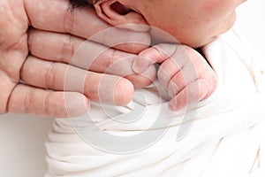 Photo of Newborn baby after birth tightly holding parents finger on white background.