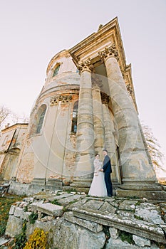 The photo of the newlyweds standing near the antique gothic church.