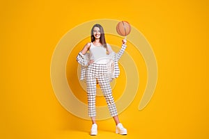 Photo of nice attractive sportive brown hair woman spinning ball playing basketball isolated over bright yellow color