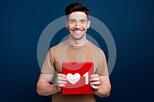 Photo of nice cheerful man wearing beige trendy clothes showing red card poster social media like isolated on dark blue