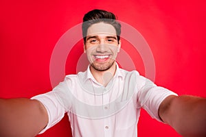 Photo of nice kind friendly self shooting man showing his teeth to you while isolated with red background