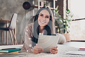 Photo of nice optimistic girl lying write tablet wear spectacles pijama at home photo