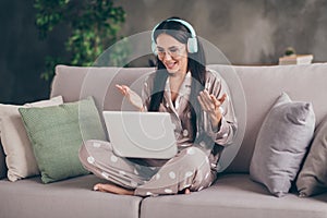 Photo of nice optimistic girl sit talk laptop wear spectacles headphones pijama at home photo