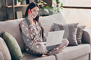 Photo of nice optimistic girl sit write laptop talk telephone wear pijama at home