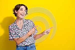 Photo of nice positive girl toothy smile look indicate fingers empty space ad isolated on yellow color background