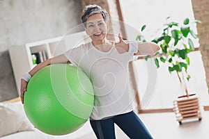 Photo of nice retired woman hold pilates ball thumb up sportswear sport healthy lifestyle workout modern apartment home