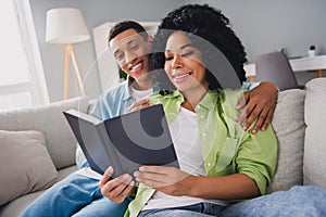 Photo of nice young man girl sit sofa hugging hold notebook read book modern interior indoors cozy daylight apartment