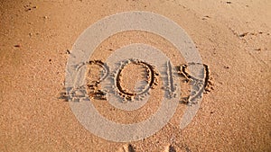 Photo of numbers 2019 written on wet sand on the sea beach. Concept of winter holidays, New Year and tourism