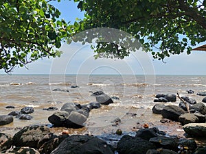 photo of the ocean with rocks and trees on either side photo