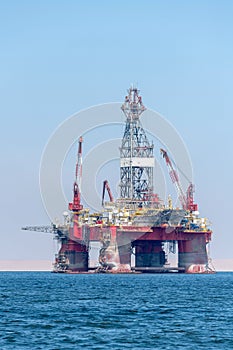 Photo of the oil derrick placed in the blue ocean water.