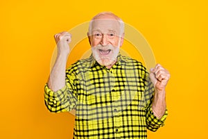Photo of old excited man happy positive smile rejoice win victory fists hands lucky success isolated over yellow color