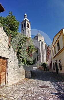 Photo of the old narrow cobblestone (natural stone) streets of medieval European small town, going to an ancient Catholic Church.
