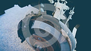 Photo of an old rusty brake disc on a car. The process of replacing brake pads on a car