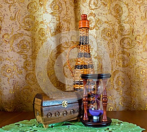 Photo of an old sandglass, bottle an casket on brown background