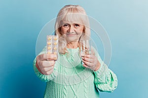 Photo of old woman give pills water glass isolated over blue background