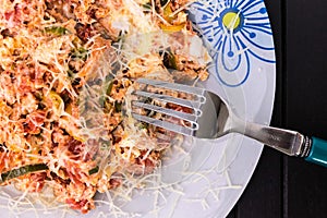 A photo of an omelette with cherry tomatoes, parsley. and grated cheese, shot from above on a rustic wooden texture with