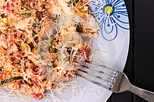 A photo of an omelette with cherry tomatoes, parsley. and grated cheese, shot from above on a rustic wooden texture with