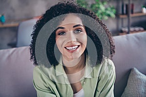 Photo of optimistic girlish cute nice woman perming hairstyle coiffure wear khaki shirt smiling positive indoors home