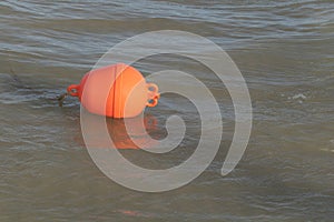 A photo of an orange plastic bouy floating in the sea