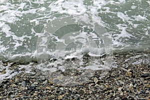 Photo out of focus. Wave sea. Water splash on the shore with a pebble beach.