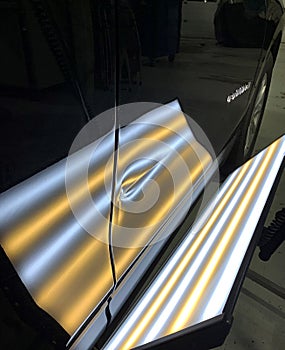 A photo of a paintless dent repair light showing a large crease in a door