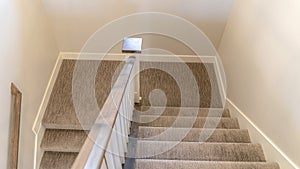 Photo Panorama U shaped staircase with handrails and gray carpet inside a home with white wall