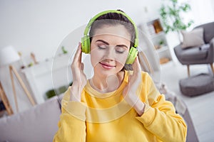 Photo of peaceful adorable girl closed eyes hands touch headphones enjoy new single house indoors