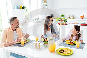 Photo of peaceful friendly cheerful family sit eat homemade food laugh good mood kitchen table apartment inside