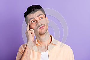 Photo of pensive minded guy finger temple look empty space wear beige shirt isolated violet color background