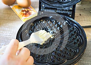 Photo of a person greasing a waffle iron pan