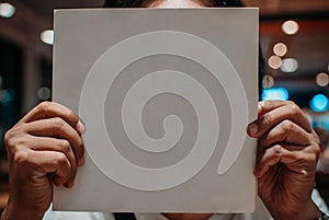 Photo of a person holding a blank white book for mock up and for commercial purposes