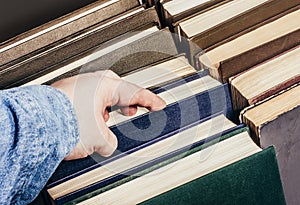 Photo of a person is holding a book in their hand in library shelf