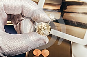 Photo of a person\'s hand in gloves holding australian coin