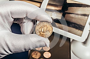 Photo of a person's hand in gloves holding a british coin