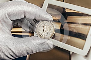 Photo of a person's hand in gloves holding a silver soviet coin